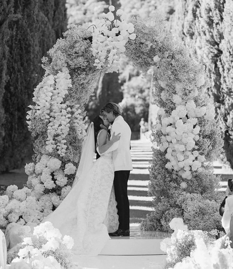 millie bobby brown and jake bongiovi kiss under floral arch at wedding