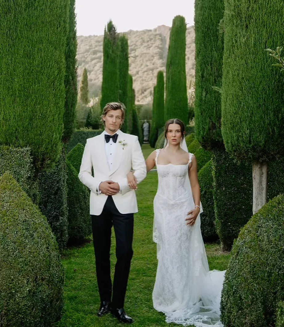 millie bobby brown wears white wedding dress posing for wedding photos in tuscan gardens next to jake bongiovi