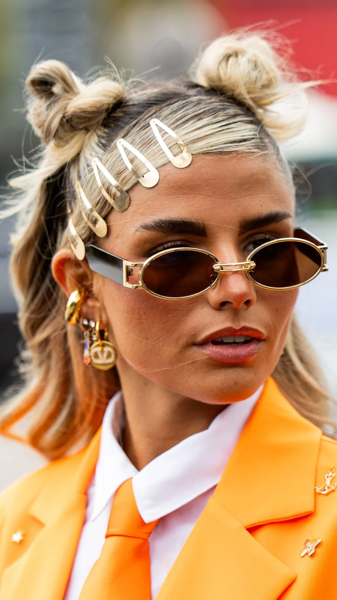 A guest wears orange tie, white button shirt, jacket with feathers, sunglasses, hair clips outside Valentino during Womenswear Spring/Summer 2025 as part of Paris Fashion Week on September 29, 2024 in Paris, France.