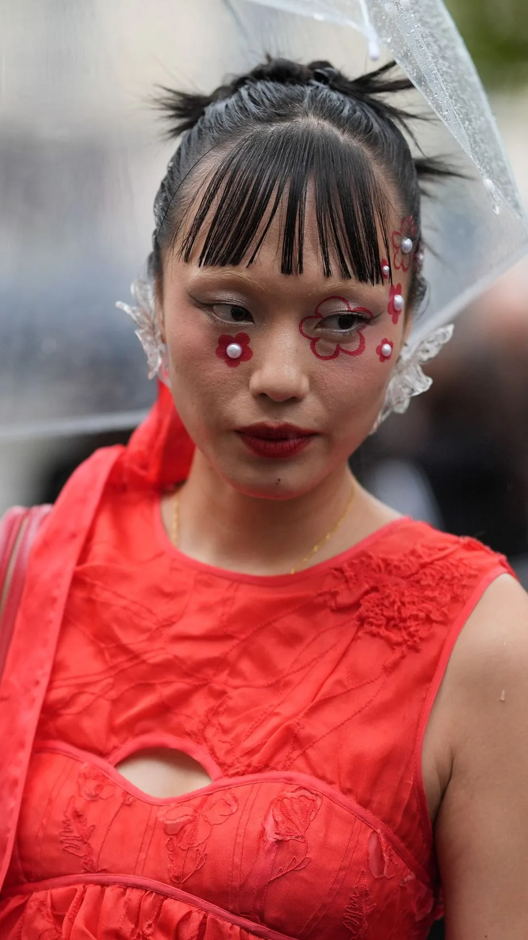 A guest wears sleeveless dress, red leather bag, gold rings, earing outside Cecilie Bahnsen, during the Paris Fashion Week Spring/Summer 2025 on September 25, 2024 in Paris, France 