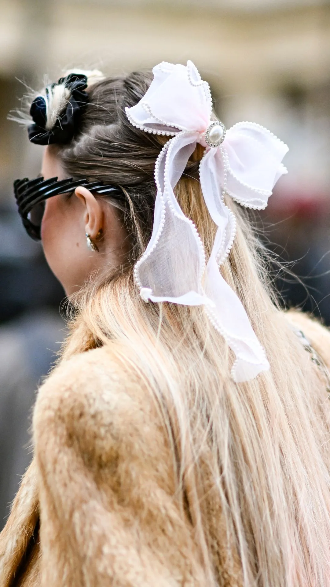  A guest is seen wearing a faux fur jacket, brown bag and pink bow and black sunglasses outside the Isabel Marant show during Womenswear Spring/Summer 2025 as part of Paris Fashion Week on September 29, 2024 in Paris, France.