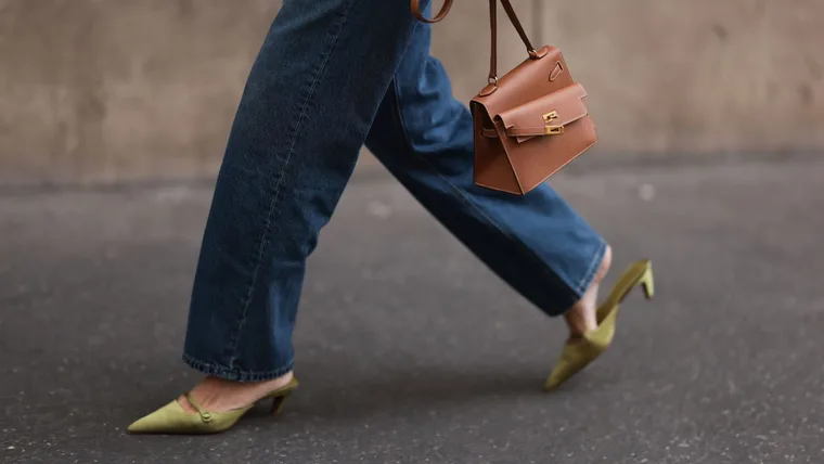 Gala Gonzalez is seen wearing a distressed brown leather jacket, straight-legged jeans, a brown leather “Kelly en Desordre“ bag with an asymmetrical detail from Hermès, a “Serpenti Viper“ ring in gold with diamonds from Bvlgari, and pointed green satin kitten heels with strap from Mango before the Hermès Womenswear Spring/Summer 2025 Show as part of Paris Fashion Week on September 28, 2024 in Paris, France.