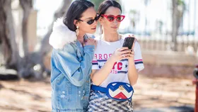 Anna Aronov wearing denim jacket and Meital Katz wearing white tshirt with Brooklyn printed, metallic midi skirt, Gucci fanny bag is seen during Tel Aviv Fashion Week on March 13, 2018 in Tel Aviv, Israel.