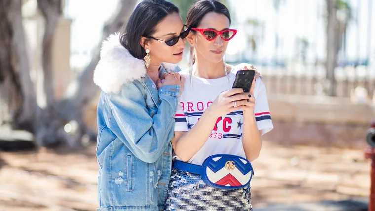 Anna Aronov wearing denim jacket and Meital Katz wearing white tshirt with Brooklyn printed, metallic midi skirt, Gucci fanny bag is seen during Tel Aviv Fashion Week on March 13, 2018 in Tel Aviv, Israel.