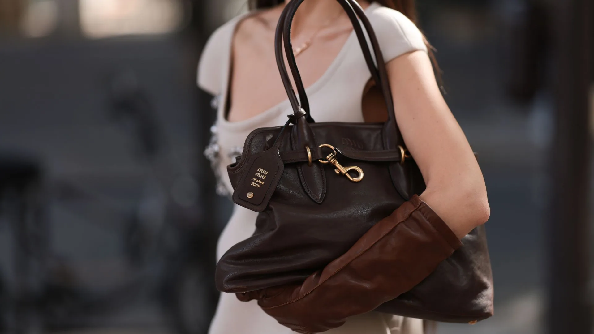 Woman holding oversized Miu Miu brown leather bag at Paris Fashion Week 