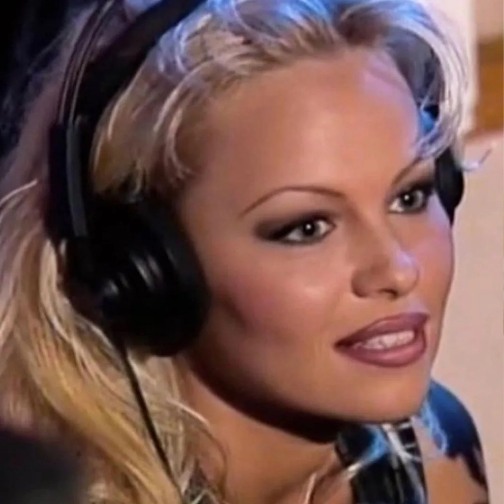 Pamela Anderson wearing headphones with a perplexed expression
