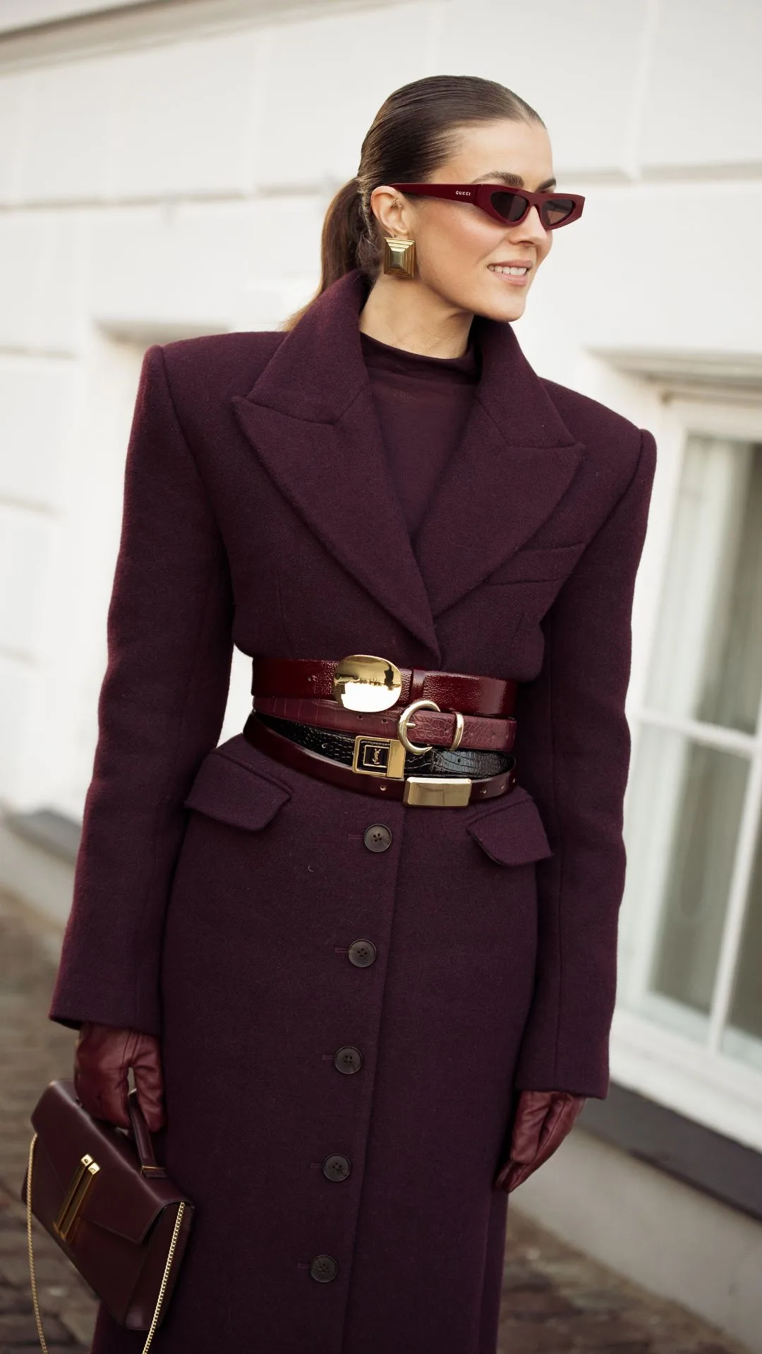 copenhagen street style fashion week autumn winter 2025 woman wears burgundy coat with several waist belts