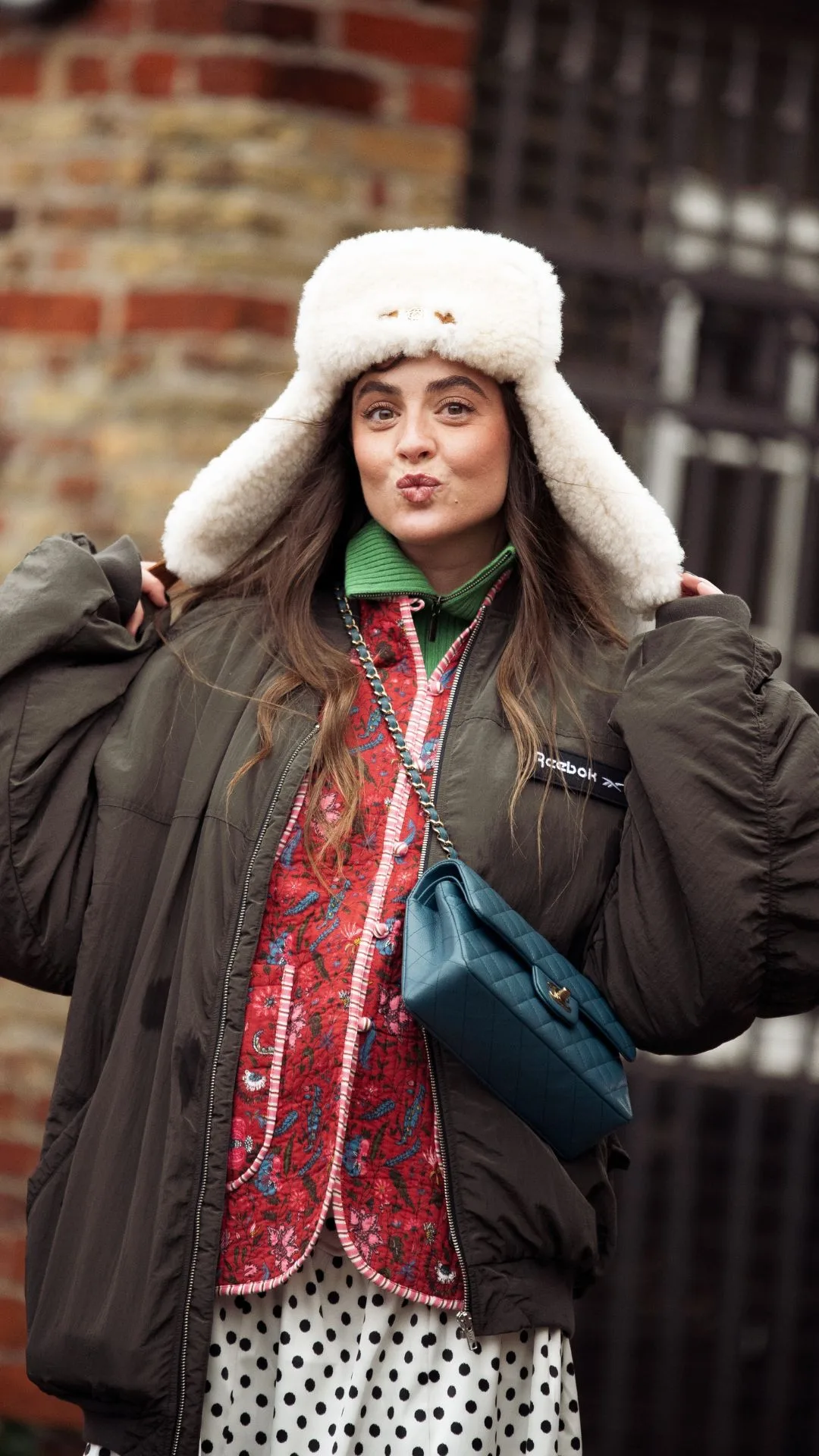 copenhagen street style fashion week autumn winter 2025 woman blows a kiss while wearing a faux fur hat