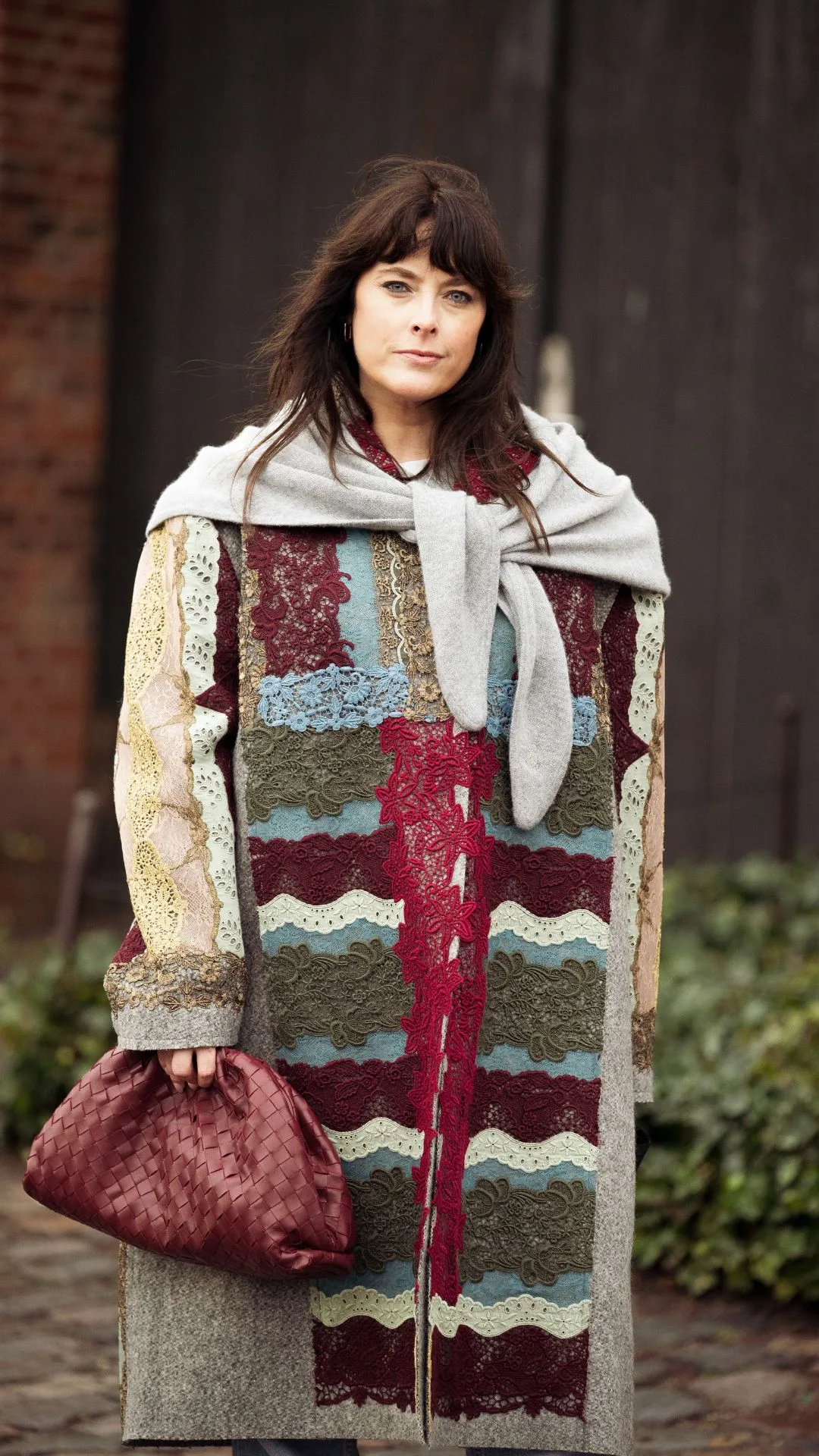 copenhagen street style fashion week autumn winter 2025 woman wears oversized coat with burgundy woven bag