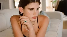 A model wearing a vintage looking Olivia Bond diamonds engagement ring with a large emerald encircled by several diamonds