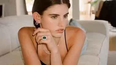 A model wearing a vintage looking Olivia Bond diamonds engagement ring with a large emerald encircled by several diamonds