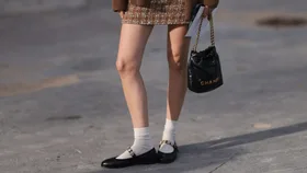 Marie von Behrens is seen wearing a brown plaid skirt, with a white top, a long brown cardigan, white short socks and black ballerinas, with a black Chanel handbag and black-brown sunglasses during the Chanel Show Womenswear Spring/Summer 2025 as part of Paris Fashion Week on October 01, 2024 in Paris, France.