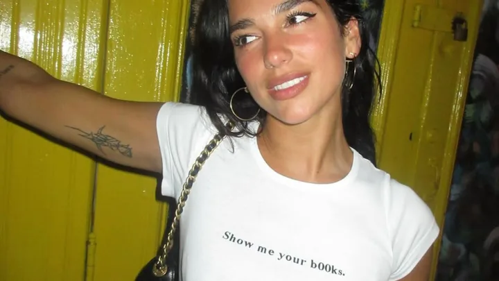 Dua Lipa wearing a graphic tee that reads "show me your books"