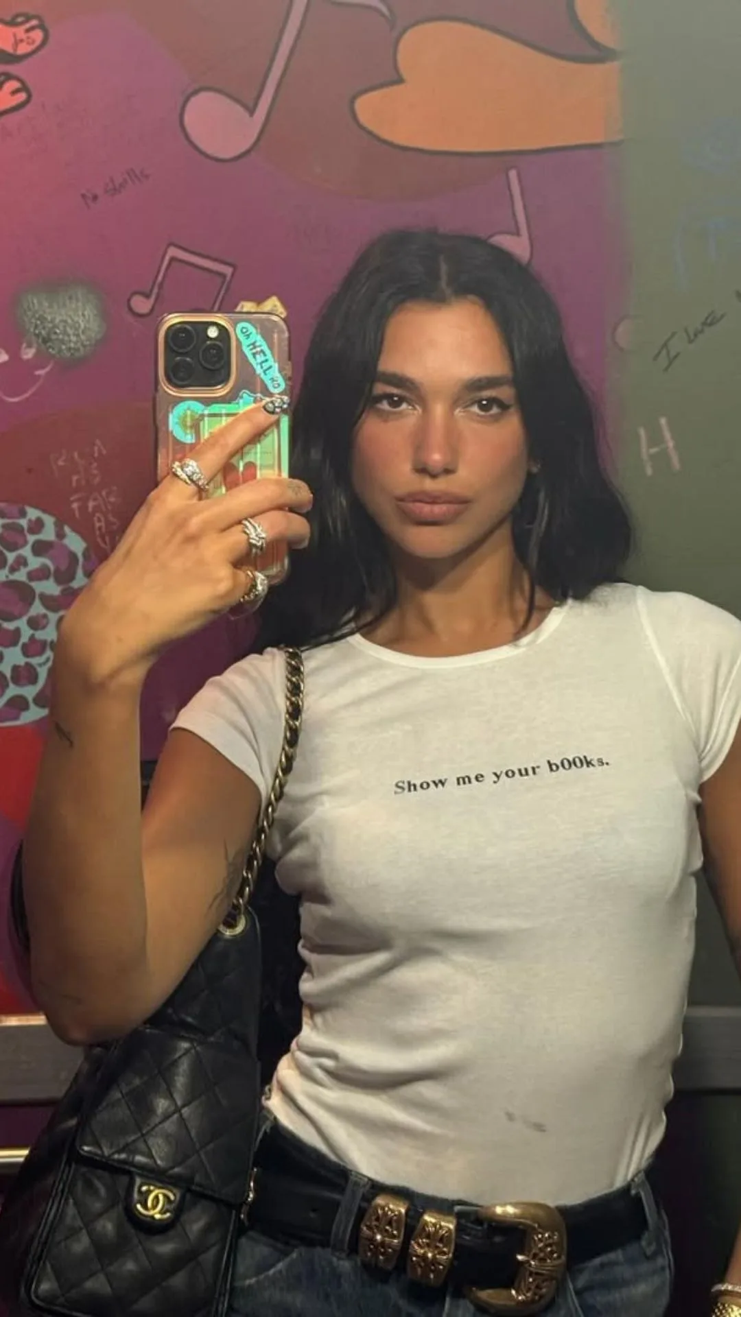 Dua Lipa wearing a graphic tee that reads "show me your books" 