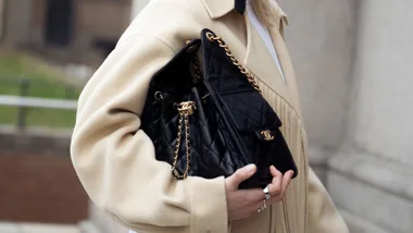 Person holding a Chanel bag and wearing a yellow coat