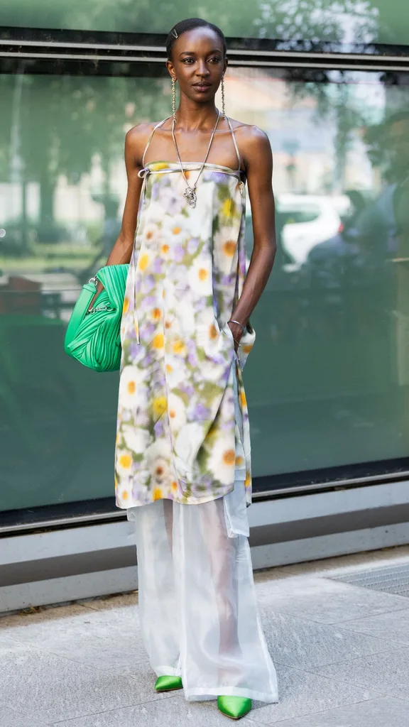A guest at Milan men's fashion week wearing a floral strapless gown over sheer white pants