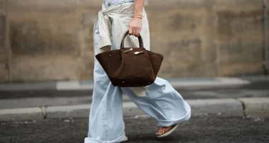 Woman wearing baggy jeans with an east west bag and thongs