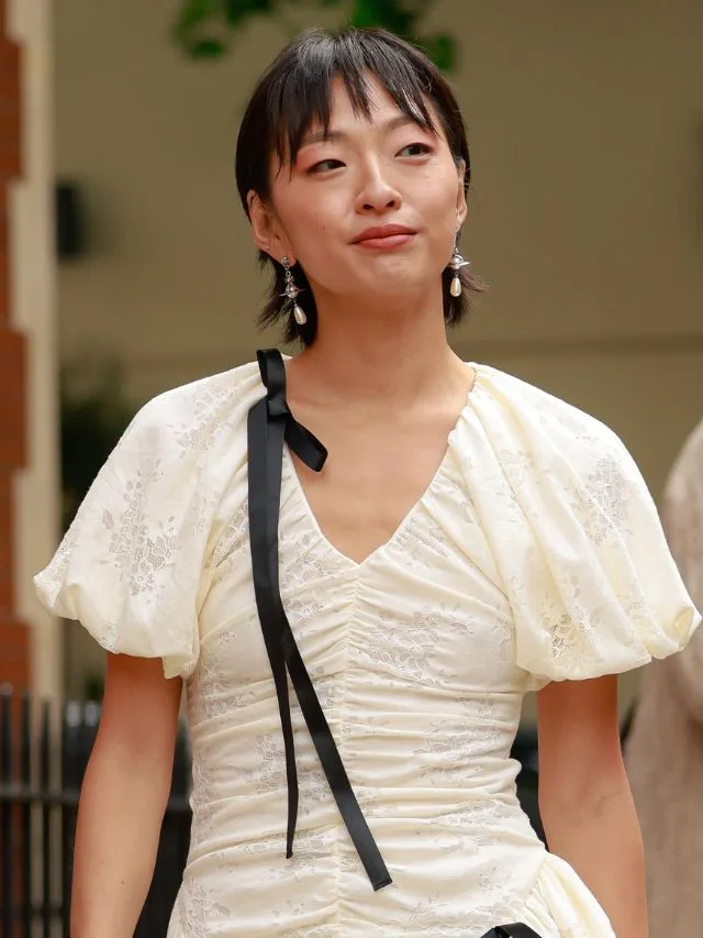 Guest at London Fashion Week wearing a white puff sleeve dress hair styled in a mullet