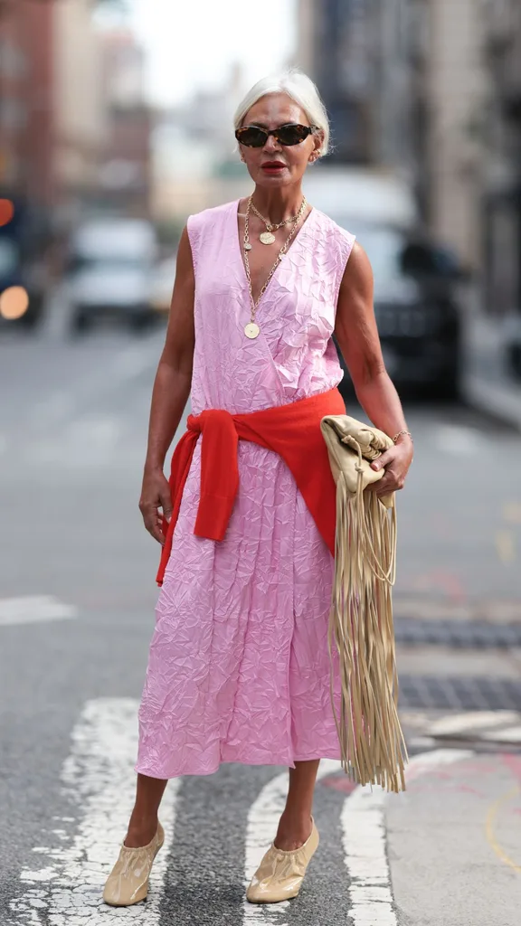 Guest at NYFW wears pink linen dress with a red sweater wrapped around the waist