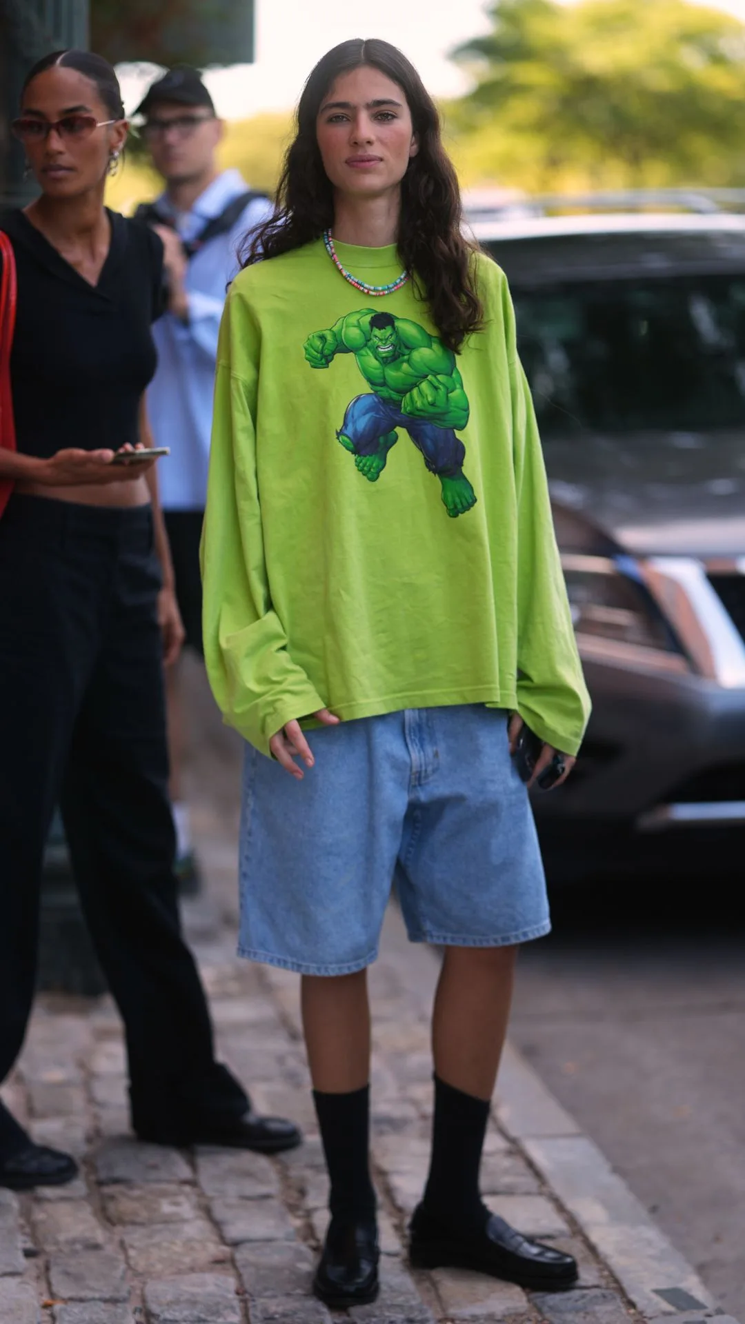 Guest at NYFW wears neon green hulk shirt with denim jorts 