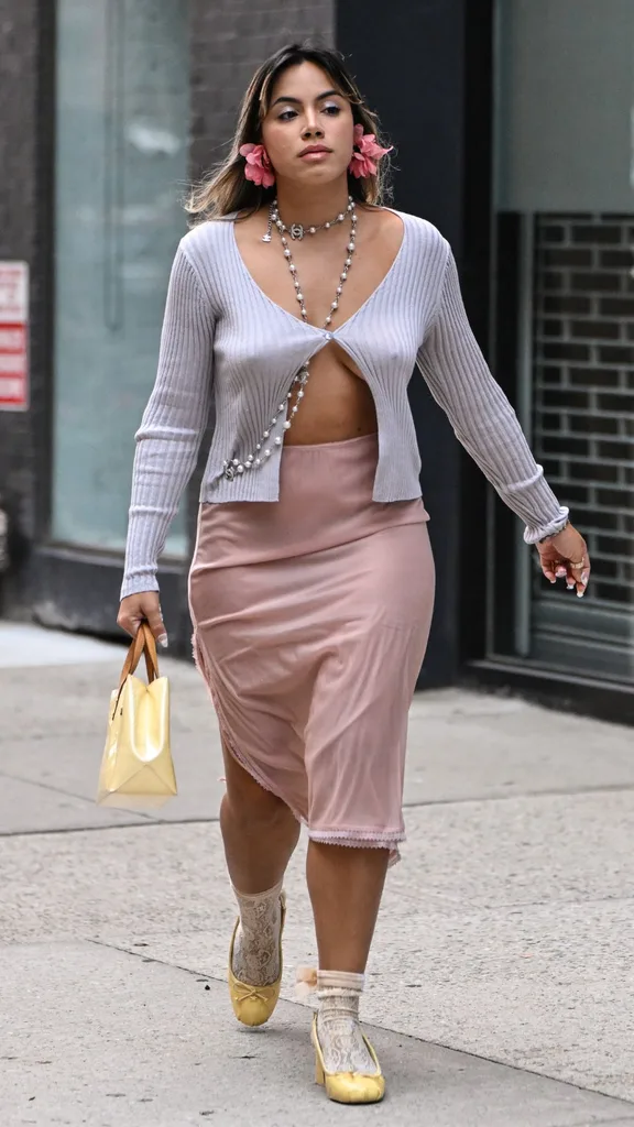 Guest at NYFW wears chanel necklace with lavender midriff baring cardigan and pink skirt