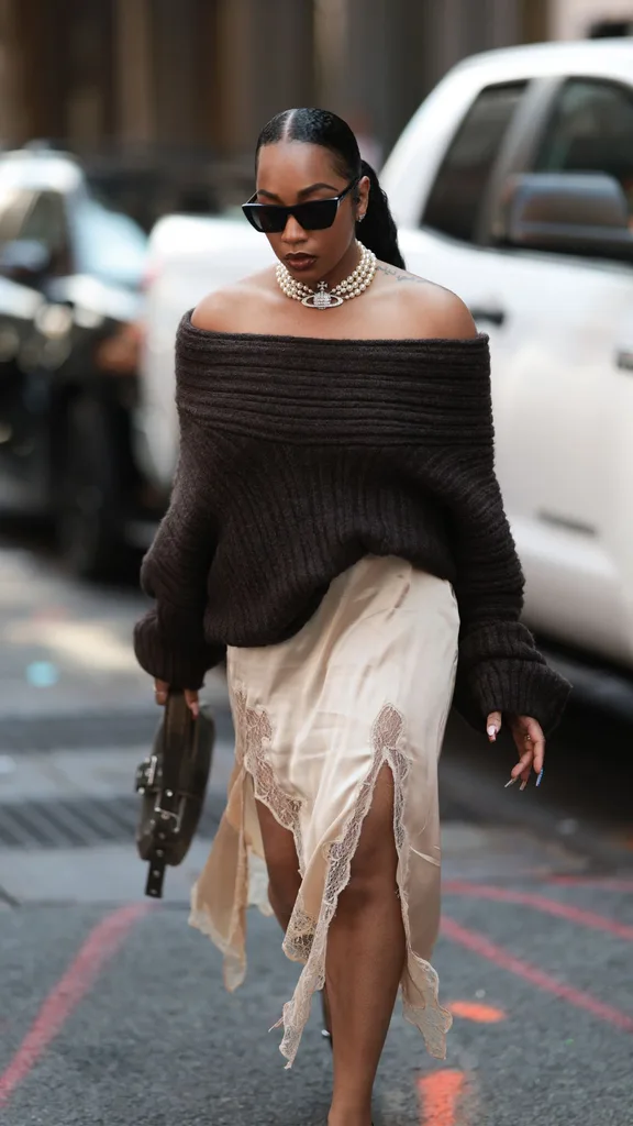 guest at nyfw wears silk skirt with off the shoulder jumper