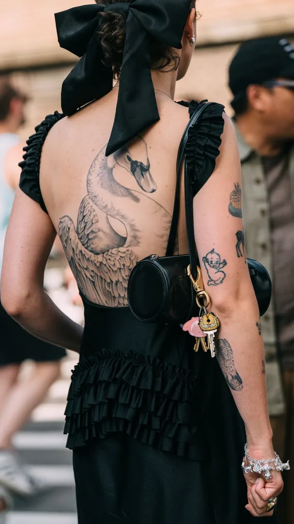 Guest at NYFW wears low backed black summer dress with tattoos visible and a black bandana