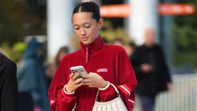 Stylish woman in red jacket on phone shops black friday sales