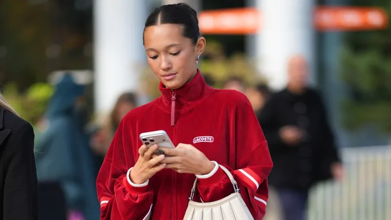 Stylish woman in red jacket on phone shops black friday sales