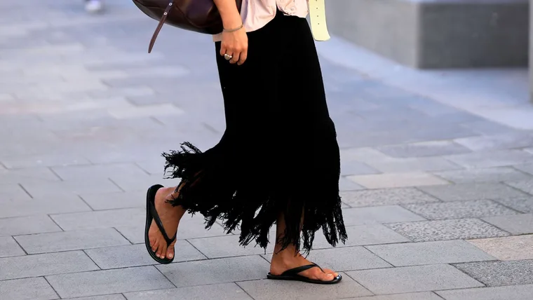Stylish woman wears black thong sandals with fringe maxi skirt