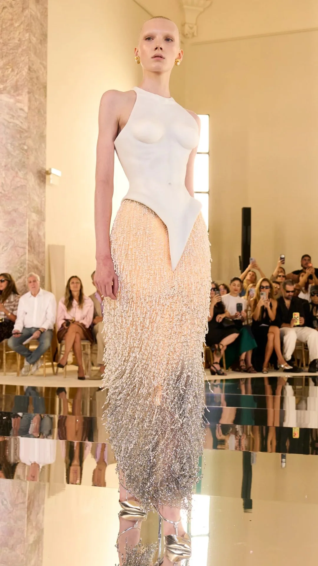 A model wears a gown with lighting beneath its sculptural beaded skirt 