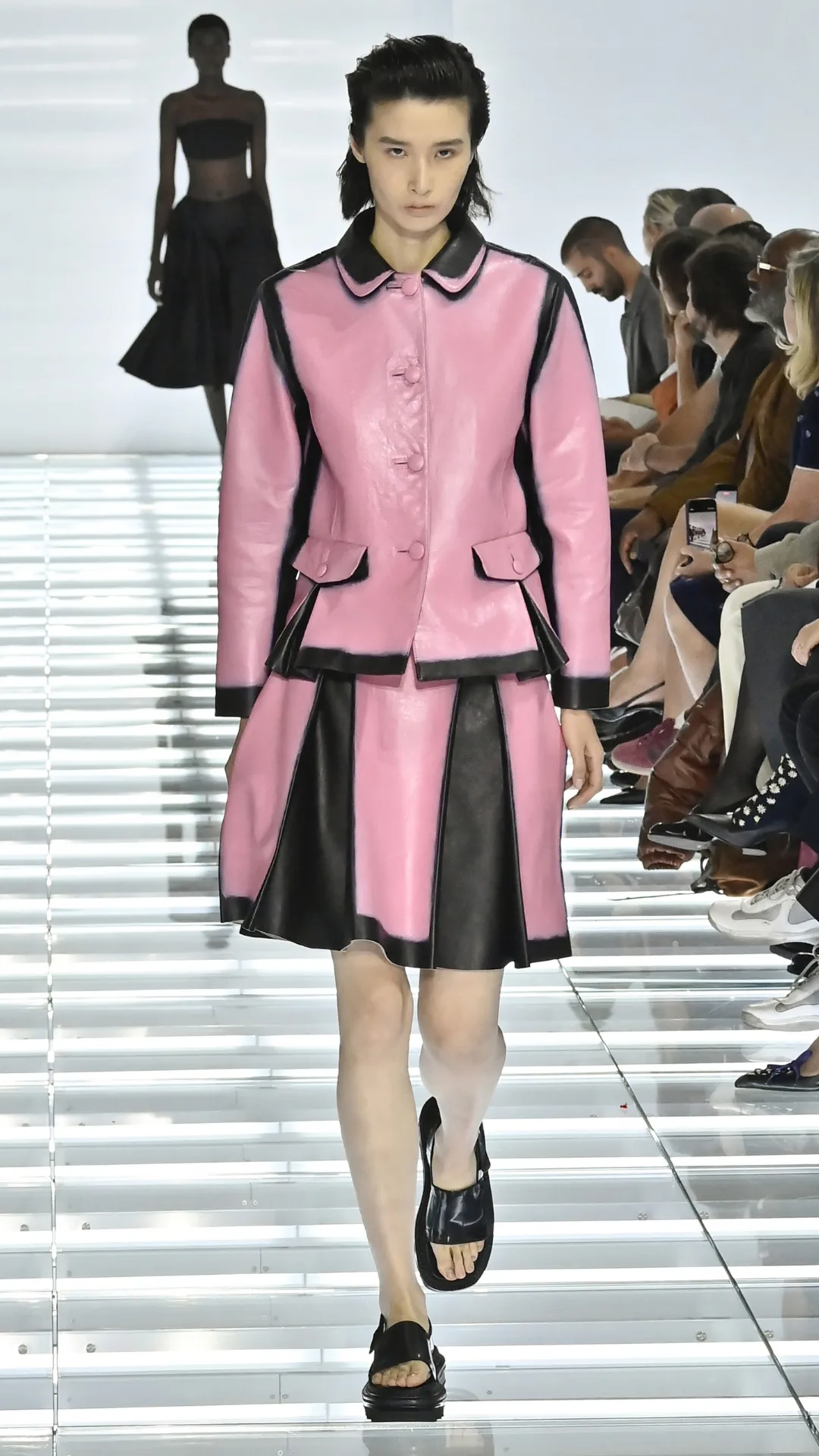 A model in a matching black and pink skirt and jacket set