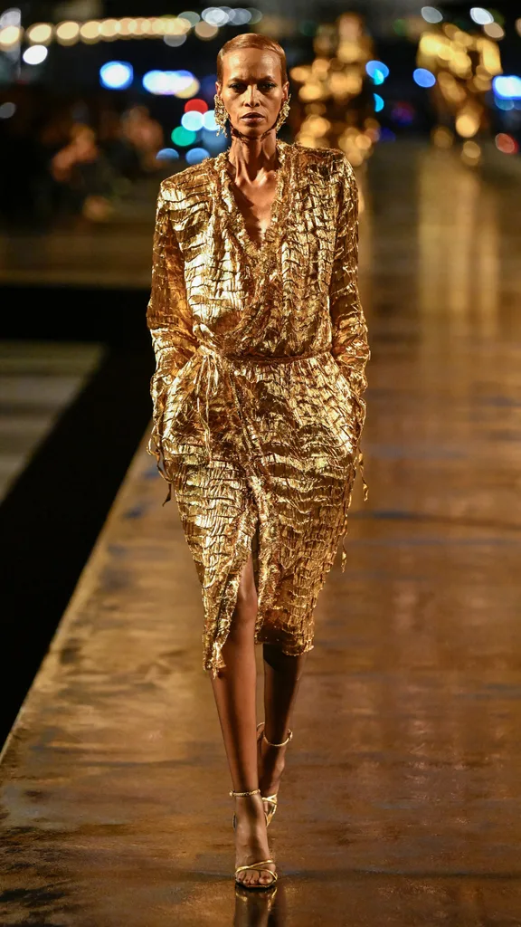A model wearing a gold jacket and skirt