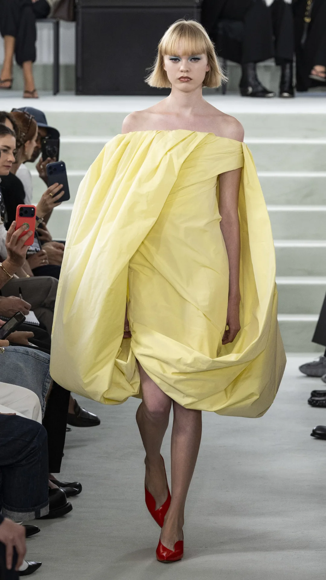 A model in a butter yellow dress with cape