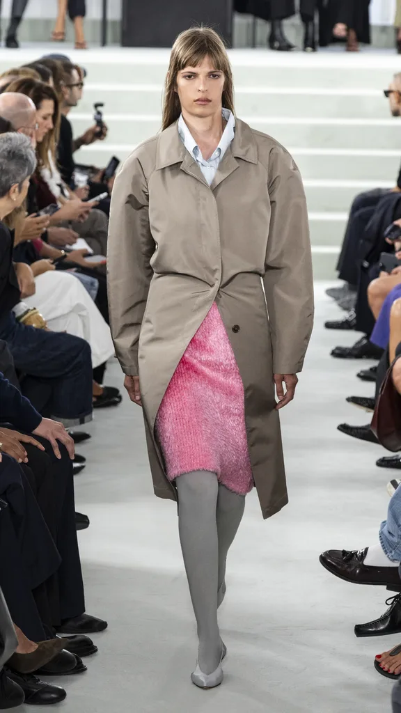A model in a pink skirt and grey trench coat