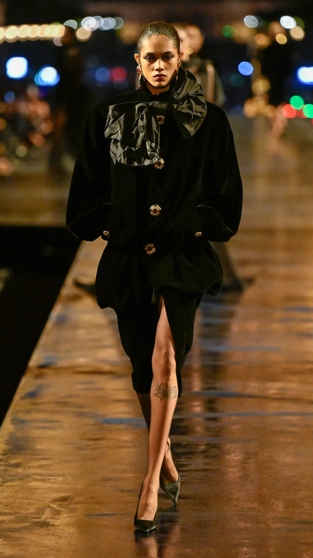 A model wearing a black jacket and skirt