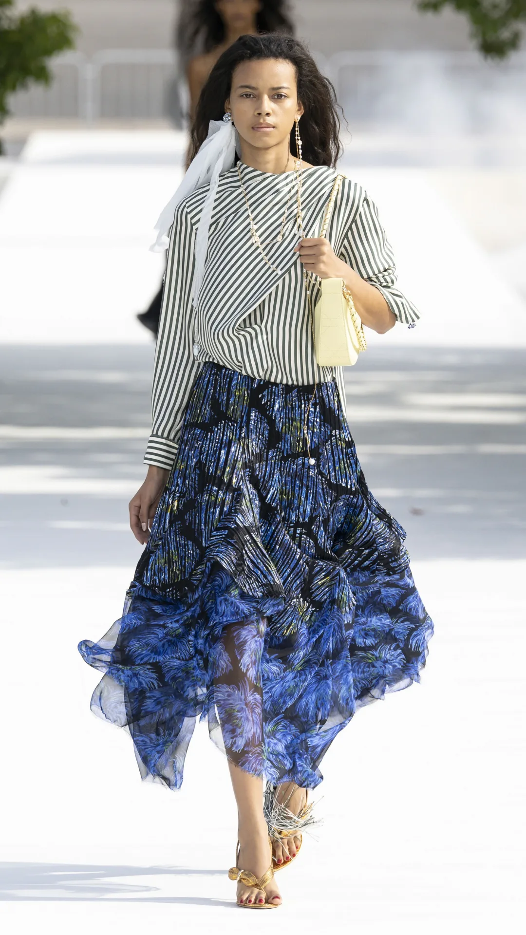 A model wears a striped shirt and blue flowy skirt