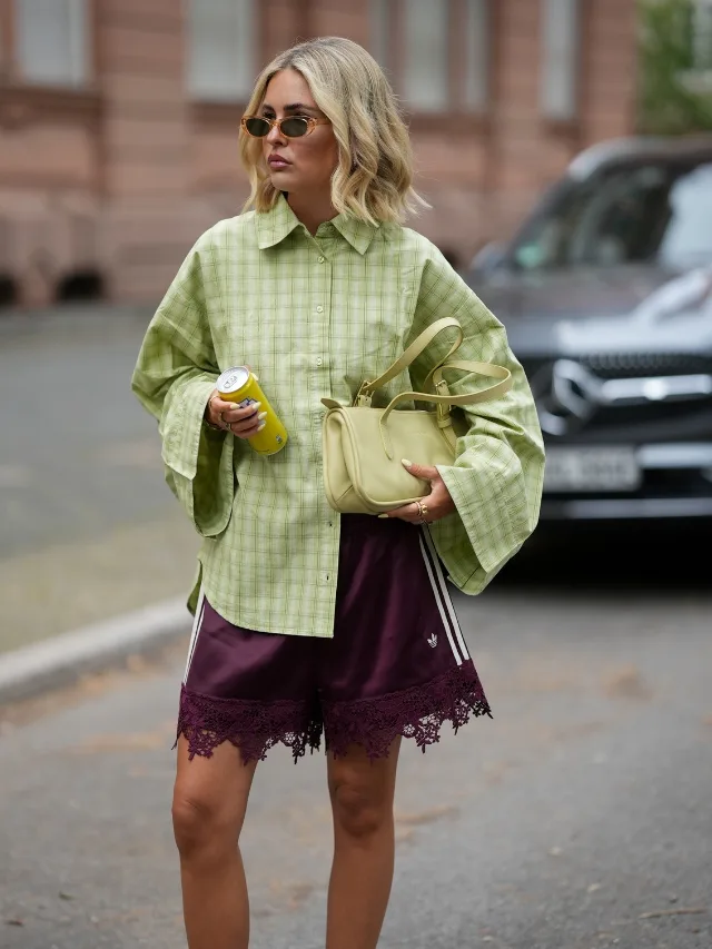 Woman wears burgundy lace shorts and a lime green button-up shirt at Copenhagen Fashion Week