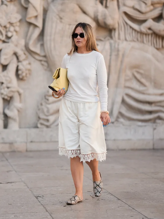 Woman wears cream lace trimmed bermuda shorts with white tshirt and animal print shoes at Copenhagen Fashion Week 2026