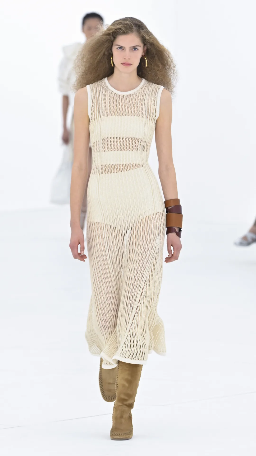 A model wearing a white dress with brown boots