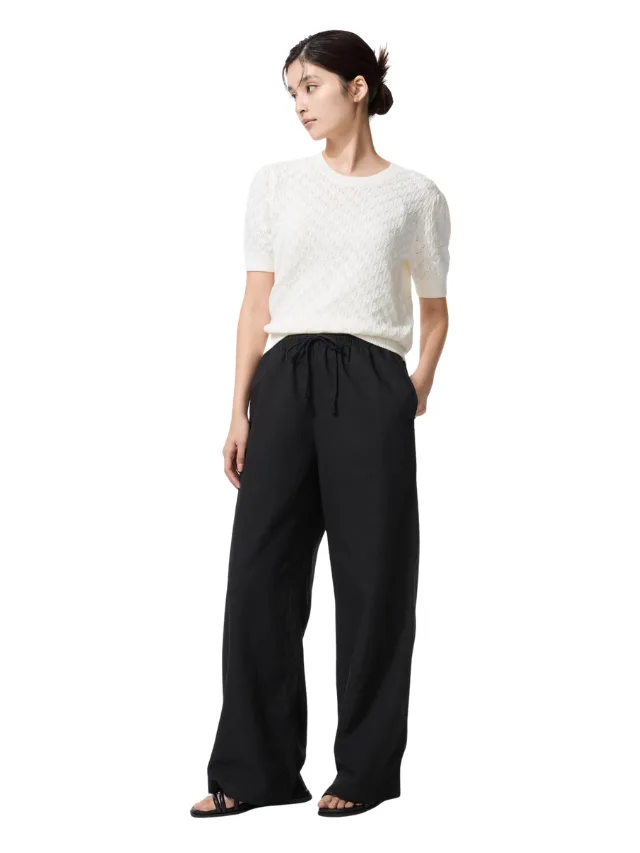A model wearing a white top and black pants
