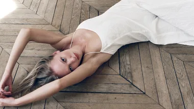 A woman with blonde hair laying in a white St. Agni bridal dress