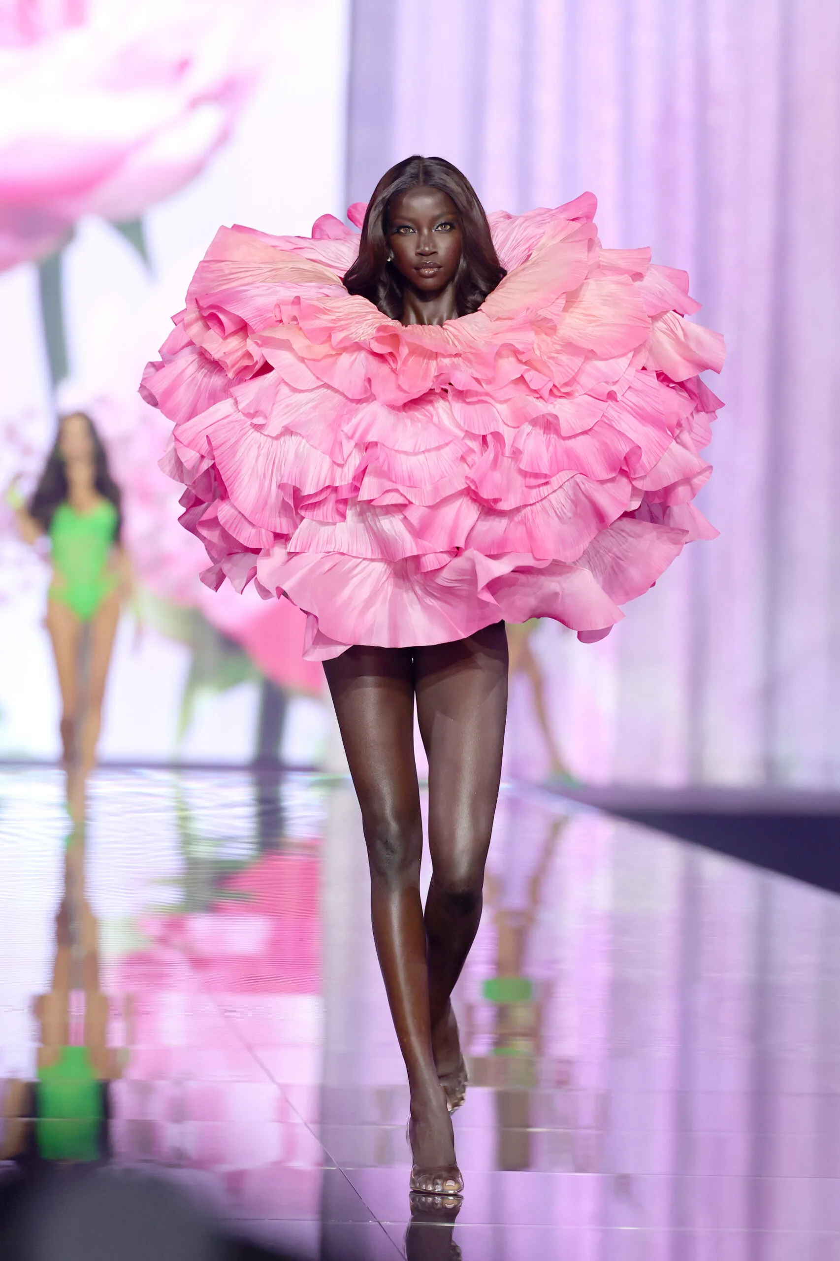 Anok Yai walks in an enormous cloud of bright pink ruffles with her face framed at the centre