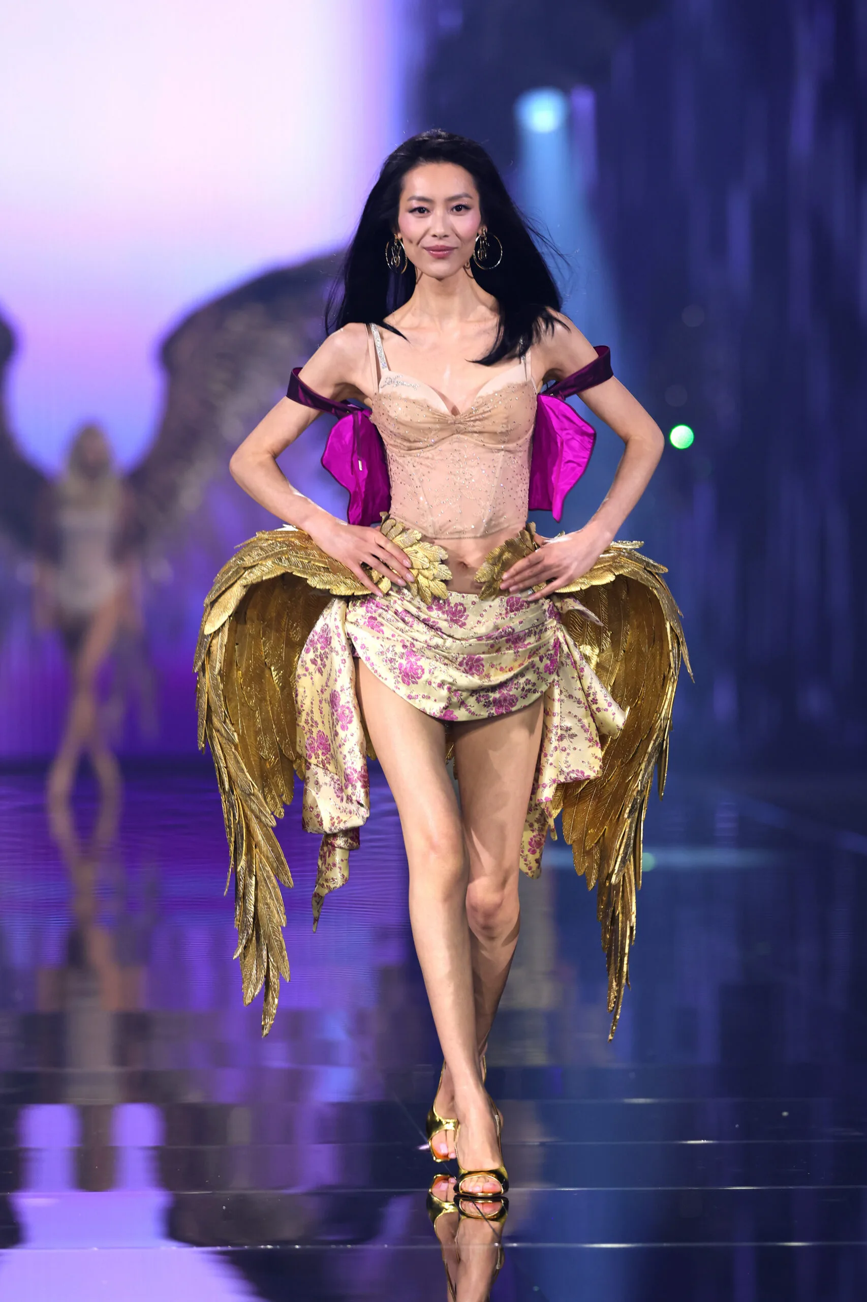 Liu Wen walks in a nude corset, floral silk draping and sculptural gold wings at her hips