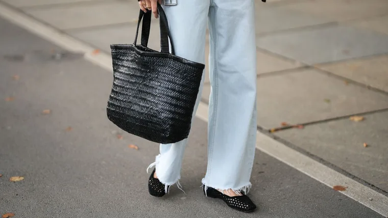 Woman carries black leather woven Evity tote bag