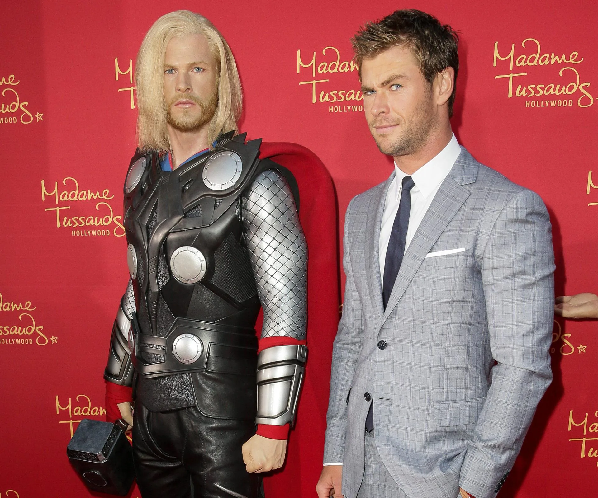 Wax figure of Thor in armor next to a person in a suit at Madame Tussauds, Hollywood.