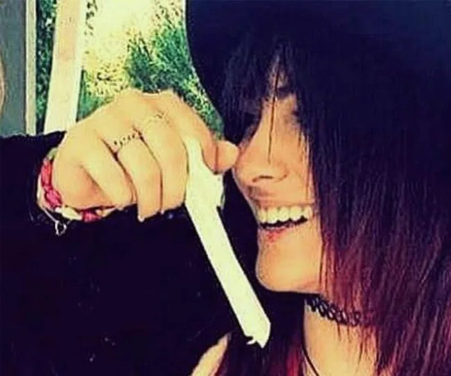 A person with dark hair and a hat smiles while holding a tampon.