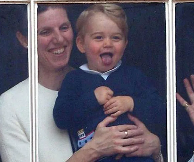 Woman holding a laughing child who is sticking out their tongue, seen through a window.