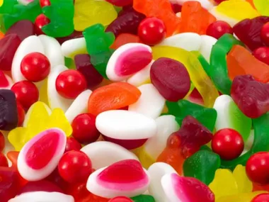 A colorful assortment of gummy candies in various shapes and bright colors, including red, green, yellow, and white.