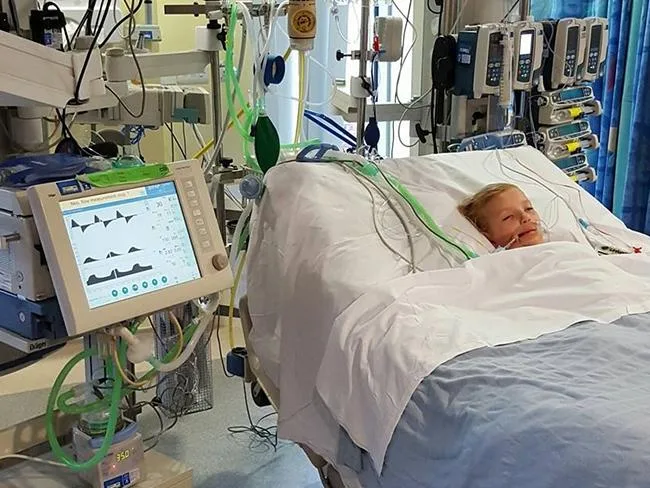Girl in hospital bed with medical equipment, fighting meningitis.